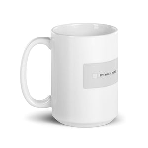 A mug with recaptcha UI that has an empty checkbox indicating the drinker is still a robot- photographed and designed by Nate DeWaele - 15oz handle on left view product